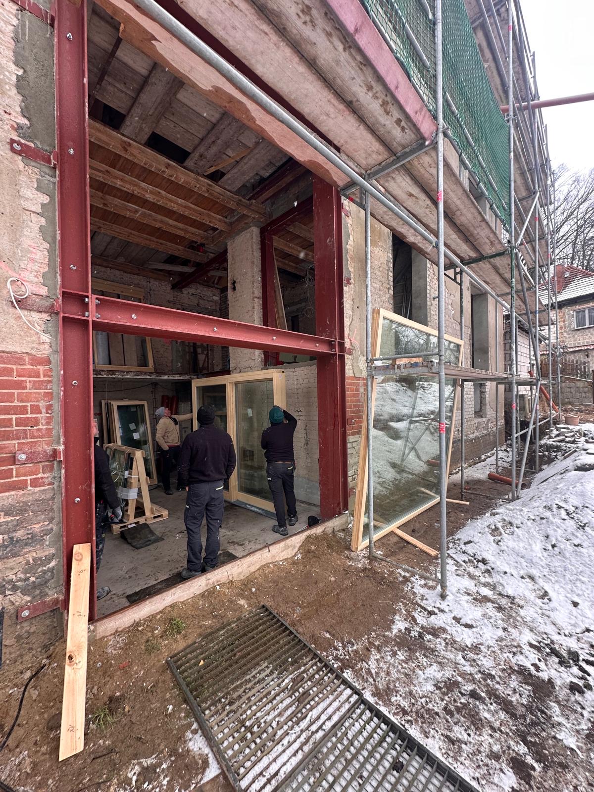 Einbau großes Holzfensterelement IV92 – Team schiebt Fenster durch Öffnung